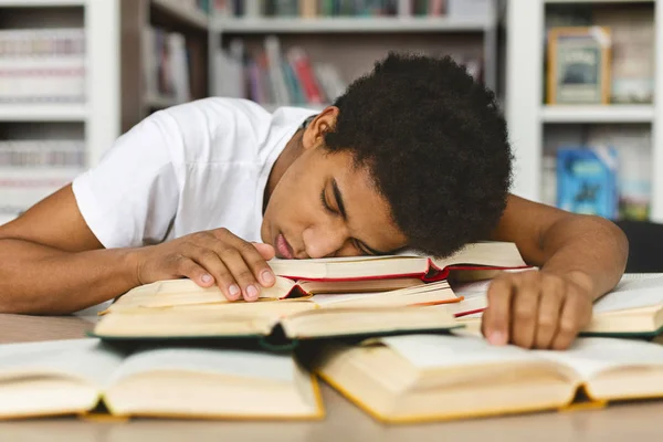 累了的家伙在图书馆的书堆上打盹 — 图库照片