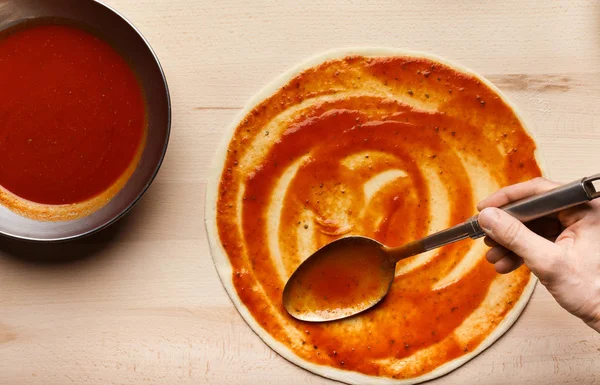 Adding sauce. Chef cooking Italian pizza, top view — Stock Photo, Image