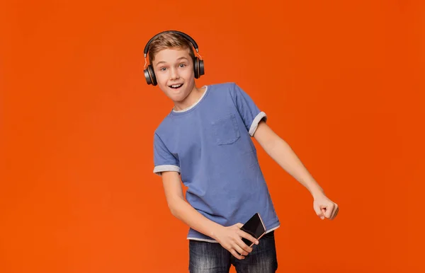 Netter Junge mit Kopfhörer, der am Telefon Musik hört — Stockfoto