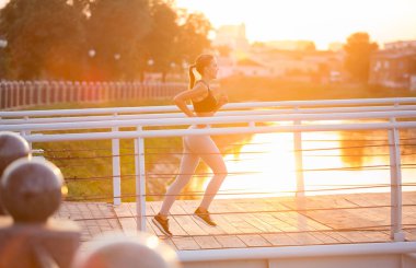 Sabah erken saatlerde köprüde Millennial Fitness kız jogging, Güneş flare