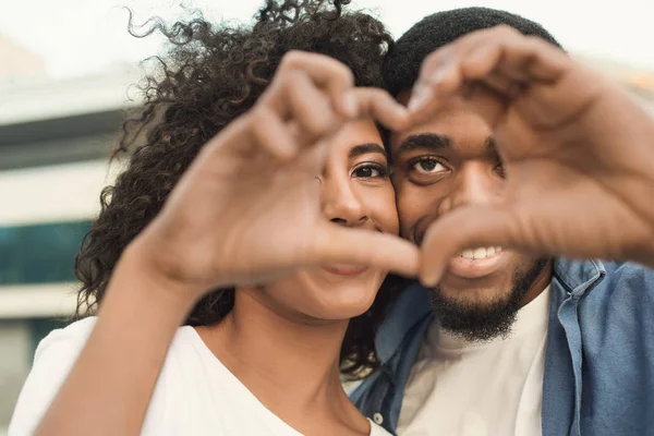 Casal amoroso olhando através da forma do coração feito com os dedos — Fotografia de Stock