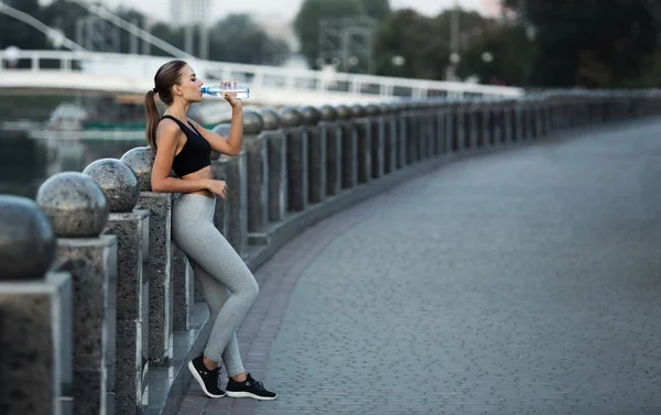 Deportiva mujer con cuerpo en forma de agua potable después de un duro entrenamiento — Foto de Stock