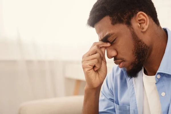 Frustrierter junger Mann berührt seinen Kopf und hält die Augen geschlossen — Stockfoto