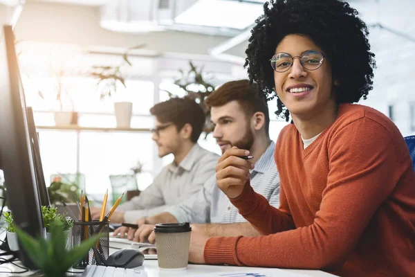 Alegre africano americano chico sonriendo a cámara en coworking —  Fotos de Stock