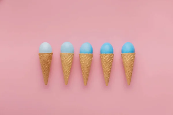 Blue easter eggs in waffle cones on pink background — Stock Photo, Image