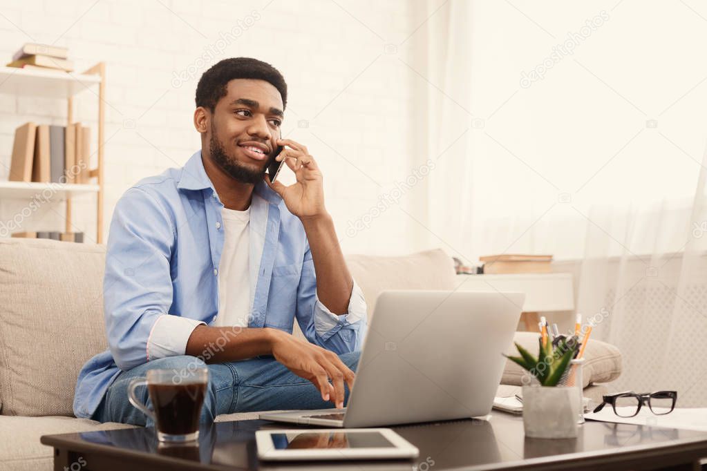 Smiling african-american guy in headphones looking at laptop