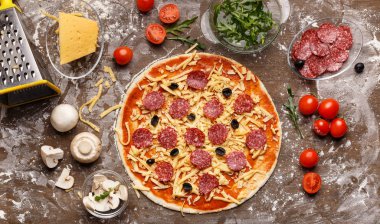 Salam ve zeytin ile ham pizza, etrafında malzemeler