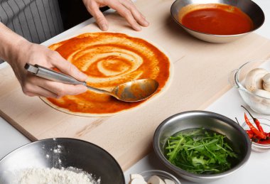 Pizza hazırlama süreci. Aşçı domates sosu yaymak