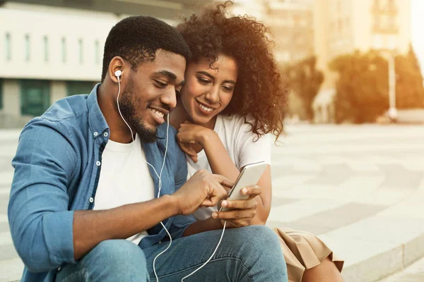 Couple listening to music with earbuds from smartphone