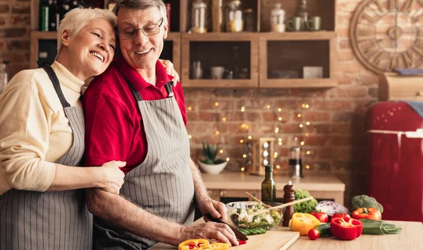 Ευγνώμων ηλικιωμένη γυναίκα αγκαλιάζει τον άντρα της στην κουζίνα — Φωτογραφία Αρχείου