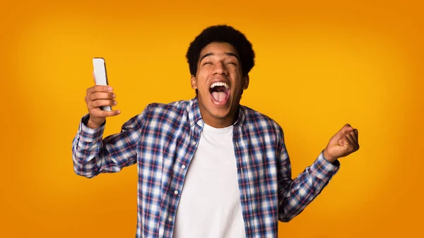 Excited student with phone celebrating victory, studio background — Stock Photo, Image