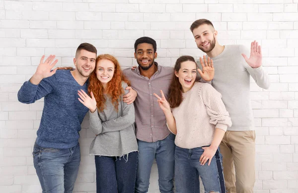 Happy friends waving hands over white wall — Stock Photo, Image