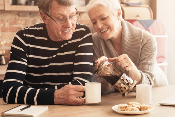 Milující starší žena nalila čerstvý čaj na pohár manželů — Stock fotografie