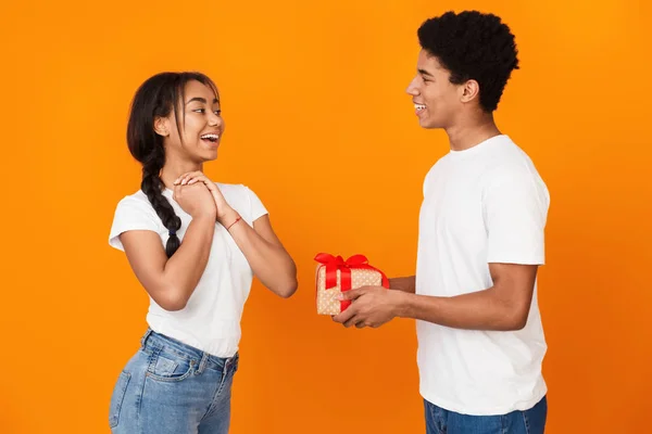 Teen kille som ger sin flickvän gåva över bakgrunden — Stockfoto