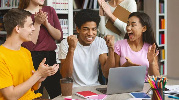 Euphorischer Student schaut Prüfungsergebnisse auf Laptop in Bibliothek — Stockfoto