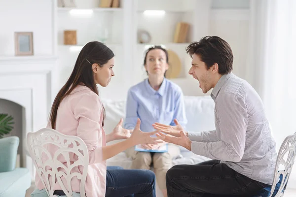 Casal discutindo durante sessão de terapia com psicólogo — Fotografia de Stock