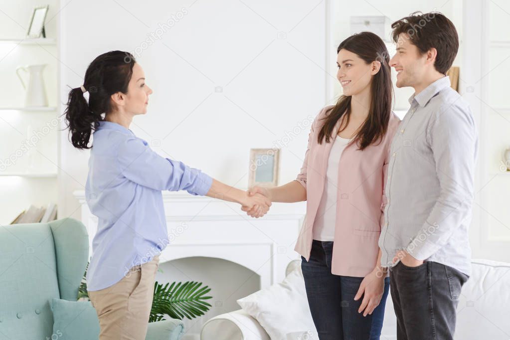 Professional psychologist and thankful couple handshaking in office