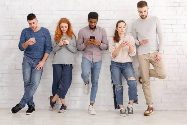 Jeunes amis élégants utilisant des appareils sur le mur de briques — Photo