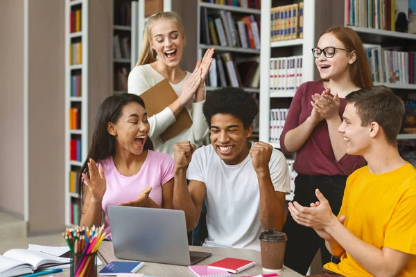 Groep jonge euphorische studenten genieten van testresultaten in de bibliotheek — Stockfoto