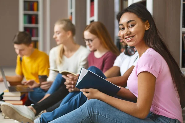 Grupa różnorodnych kolegów siedzących na podłodze w bibliotece — Zdjęcie stockowe