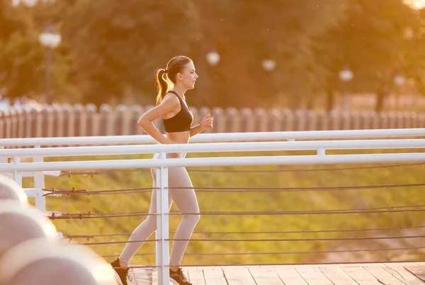 Hermosa mujer joven deportiva corriendo por el puente — Foto de Stock