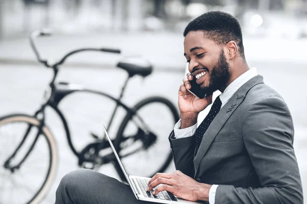Empresário afro-americano usando laptop, tendo pausa ao ar livre — Fotografia de Stock
