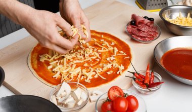 İtalyan yemeği. Şef pizzarende peynir ekleyerek