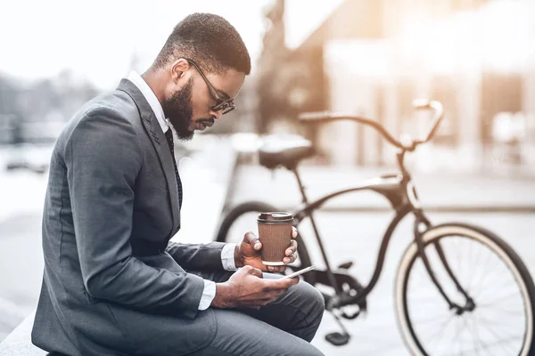 自転車で座っているコーヒーとスマートフォンを持つビジネスマン — ストック写真