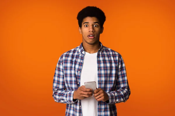 Impresionado afroamericano chico mensajes de texto en el teléfono, mirando a la cámara — Foto de Stock