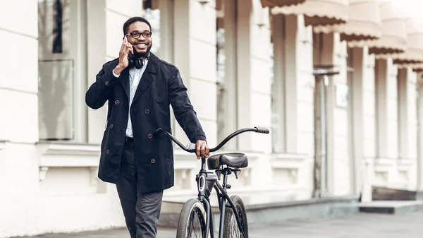 Empresário afro-americano falando ao telefone, andando de bicicleta — Fotografia de Stock