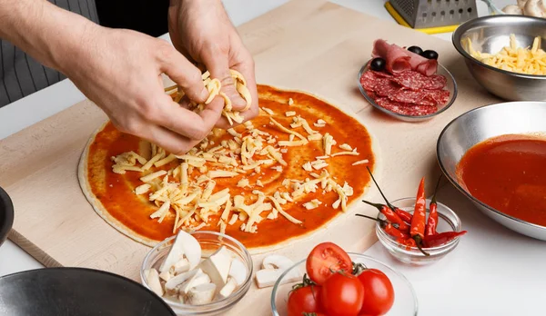 Italský pokrm. Kuchař přidává strouhané sýry na pizzu — Stock fotografie