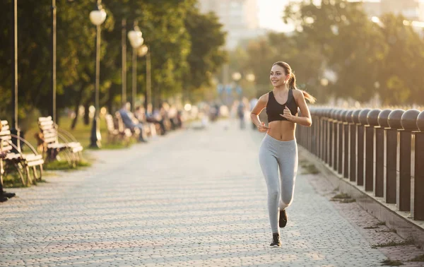 Joven mujer deportiva corriendo en muelle en el parque de la ciudad — Foto de Stock