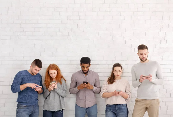 Εθισμός στο διαδίκτυο. Οι μαθητές με τα smartphones πάνω από άσπρο τοίχο — Φωτογραφία Αρχείου