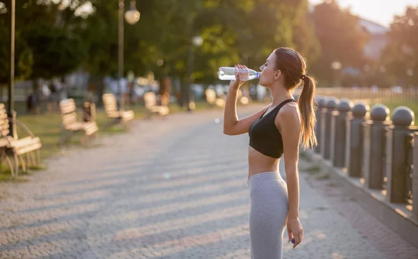 Deportiva mujer milenaria bebiendo agua pura después del entrenamiento — Foto de Stock