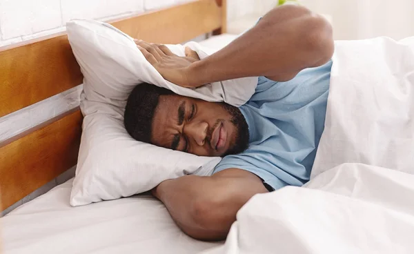 Молодой человек в постели прячется под подушкой — стоковое фото