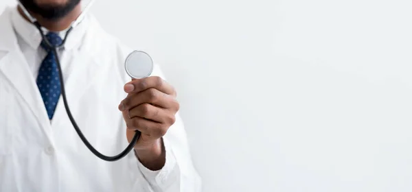 Mannelijke arts luisteren met stethoscoop over lichte achtergrond — Stockfoto
