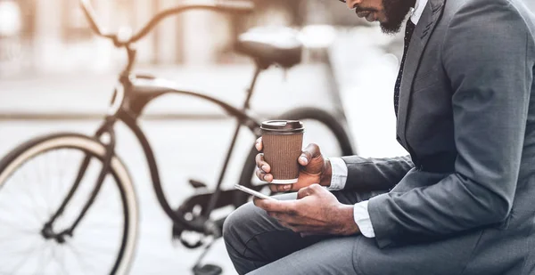 Empresário com café e smartphone sentado perto da bicicleta — Fotografia de Stock