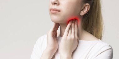 Woman with thyroid gland problem, touching her neck