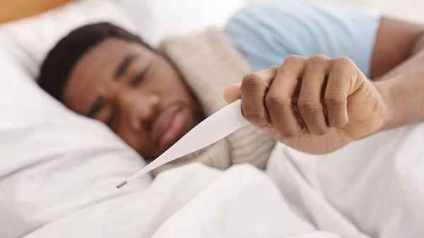 Kranker mit Fieber kontrolliert seine Temperatur im Bett — Stockfoto