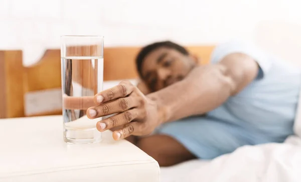 若い男がベッドの中で水を飲んで — ストック写真