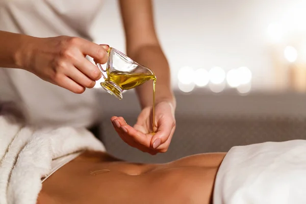 Masseur pouring oil on hand, preparing for massage — Stock Photo, Image