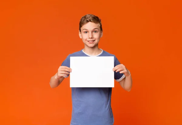 Słodkie uśmiechnięty chłopak trzyma biały pusty afisz — Zdjęcie stockowe