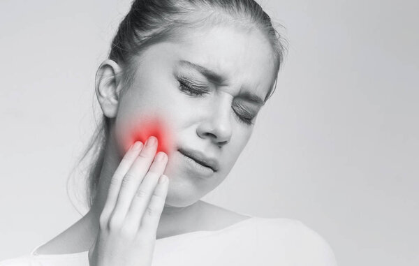 Young woman suffering from strong tooth ache