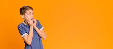 Korkmuş çocuk elleri ile ağız kapsayan, korku ile bir kenara bakıyor