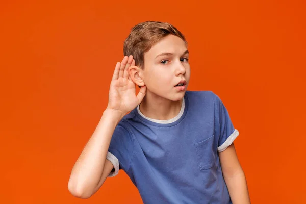 Nysgerrig snoopy skoledreng holder hånd på øret - Stock-foto