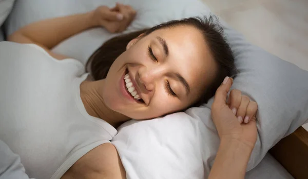 Mujer despertando por la mañana, estirándose, acostada en la cama —  Fotos de Stock