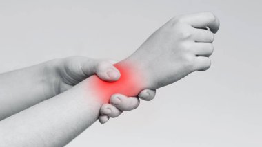 Genç bir kadın bileğine masaj yapıyor, yakın plan.