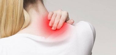 Genç bir kadın ağrıyan boynuna masaj yapıyor.