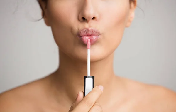 Young woman applying lip gloss on her lips — 스톡 사진