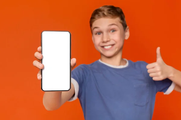 Pozytywny nastoletni chłopiec pokazując pusty ekran telefonu i kciuk w górę — Zdjęcie stockowe